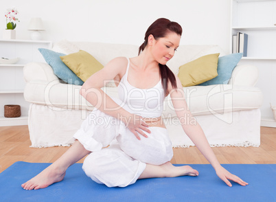 Good looking red-haired female stretching in the living room