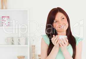 Attractive red-haired woman enjoying her breakfast in the kitche