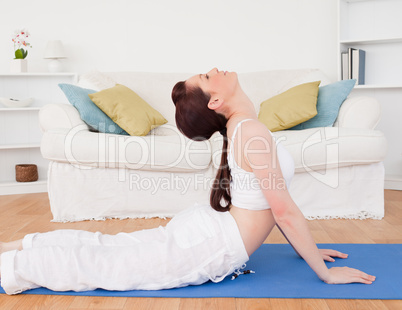 Charming red-haired female stretching in the living room