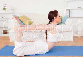 Young gorgeous red-haired female stretching in the living room
