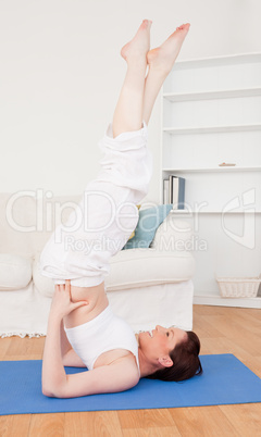 Young attractive red-haired female stretching in the living room