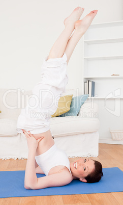 Young good looking red-haired female stretching in the living ro