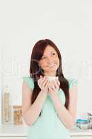 Beautiful red-haired woman enjoying her breakfast in the kitchen