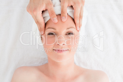 Closeup of a young good looking red-haired woman receiving a mas