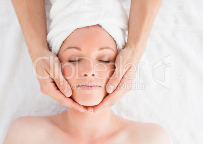 Closeup of a young pretty red-haired woman receiving a massage i