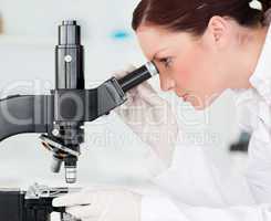 Attractive red-haired scientist looking through a microscope