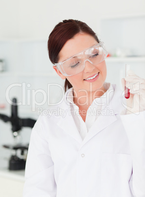 Pretty red-haired scientist looking at the camera while holding