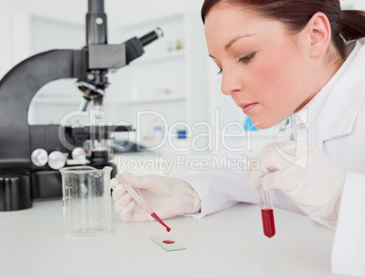 Cute red-haired female scientist doing an experiment in a lab