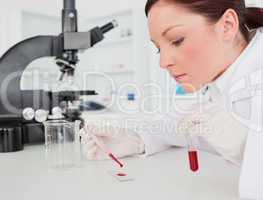Cute red-haired female scientist doing an experiment in a lab