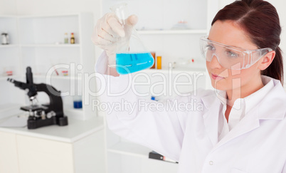 Cute female scientist looking at a beaker in a lab