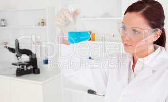 Cute female scientist looking at a beaker in a lab