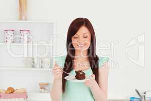 Beautiful red-haired woman eating some cake in the kitchen