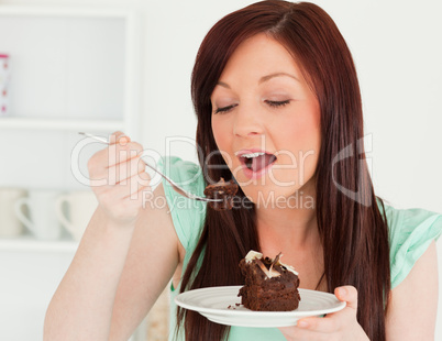 Gorgeous red-haired woman eating some cake in the kitchen