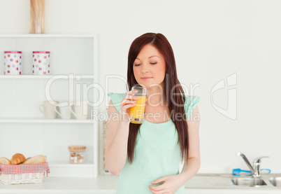 Attractive red-haired woman enjoying a glass of orange juice in