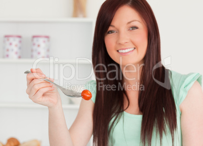 Good looking red-haired woman cutting eating a cherry tomato in