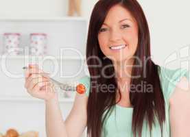 Good looking red-haired woman cutting eating a cherry tomato in