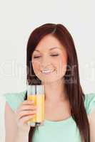 Gorgeous red-haired woman enjoying a glass of orange juice in th