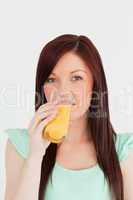 Good looking red-haired woman drinking a glass of orange juice i