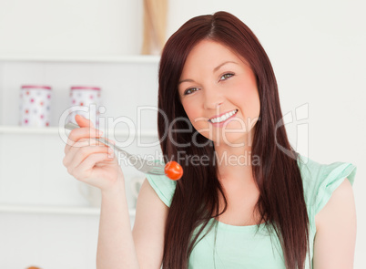 Attractive woman cutting eating a cherry tomato in the kitchen