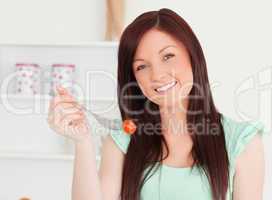 Attractive woman cutting eating a cherry tomato in the kitchen