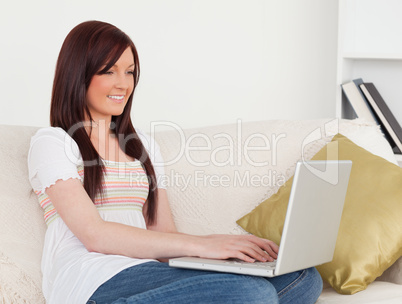 Good looking red-haired woman relaxing with her laptop while sit