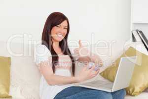 Attractive woman sitting on a sofa is going to make a payment on