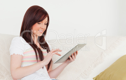 Good looking red-haired woman relaxing with her tablet while sit