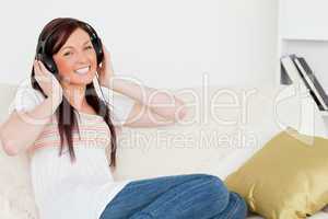 Attractive red-haired woman listening to music with headphones w