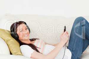 Good looking red-haired woman listening to music with headphones