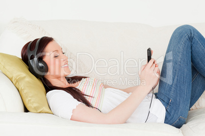 Beautiful red-haired woman listening to music with headphones wh