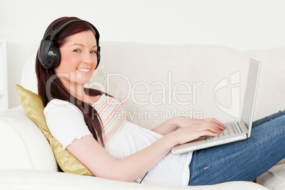 Good looking red-haired woman listening to music with headphones