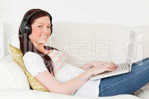 Good looking red-haired woman listening to music with headphones