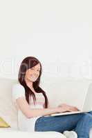 Charming red-haired woman relaxing with her laptop while sitting