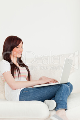 Smiling red-haired woman relaxing with her laptop while sitting