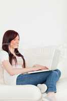 Smiling red-haired woman relaxing with her laptop while sitting