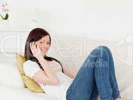 Charming red-haired woman having a conversation on the phone whi
