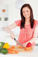 Beautiful red-haired woman cutting some carrots in the kitchen