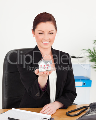 Young attractive red-haired woman in suit holding a miniature ho Young attractive red-haired woman in suit holding a miniature ho