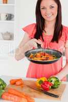 Good looking red-haired woman cooking vegetables in the kitchen