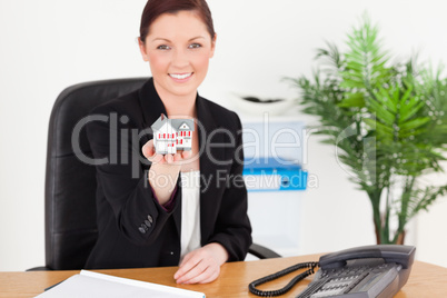 Young good looking red-haired woman in suit holding a miniature