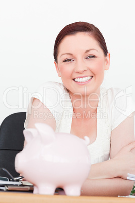 Young smiling red-haired female posing while sitting in an offic