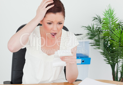 Young attractive red-haired female being surprised by the amount