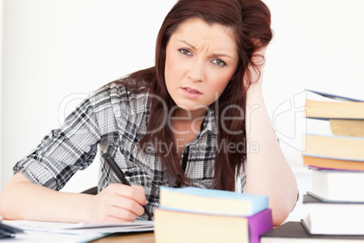 Attractive red-haired girl being upset while studying for an exa