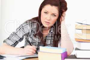 Attractive red-haired girl being upset while studying for an exa