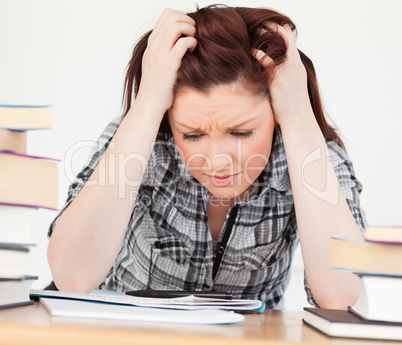 Gorgeous red-haired girl being upset while studying for an exami