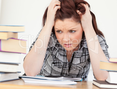 Attractive red-haired female being upset while studying for an e