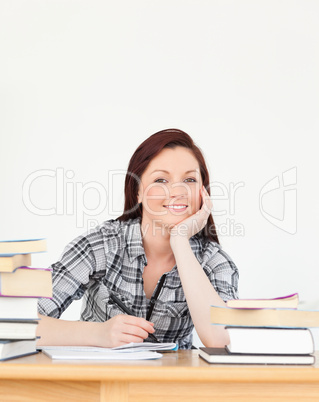 Beautiful joyful red-haired girl studying for an examination