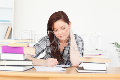 Beautiful happy red-haired girl studying for an examination