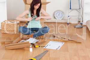 Beautiful red-haired girl using a hammer for diy at home