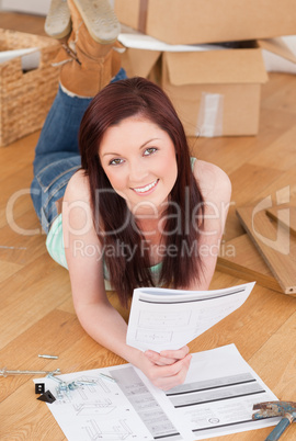 Good looking red-haired girl posing while reading a manual befor